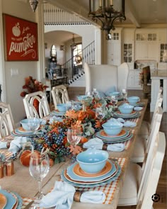 a dining room table set with blue and orange plates, place settings and napkins