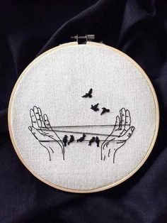 two hands holding something in the air with birds flying over them on a black cloth