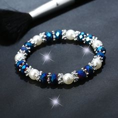 a blue and white beaded bracelet next to a brush on a black tablecloth