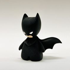 a small toy batgirl is posed on a white surface