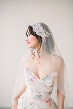 a woman in a wedding dress with a veil over her head and flowers on it