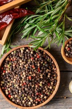 two wooden bowls filled with lentils next to garlic and peppers on a wood table