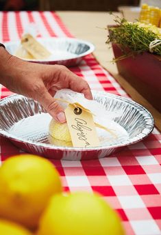 a person is holding a piece of paper in front of some lemons on a table