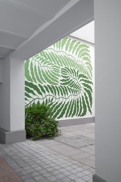 a green and white mural on the side of a building next to a potted plant