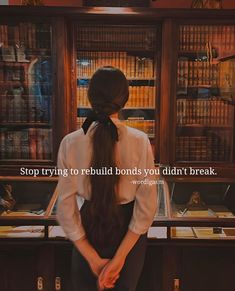 a woman with long hair standing in front of a bookshelf