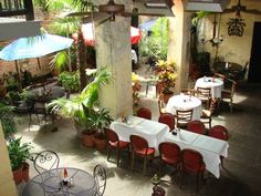 an outdoor dining area with tables, chairs and umbrellas