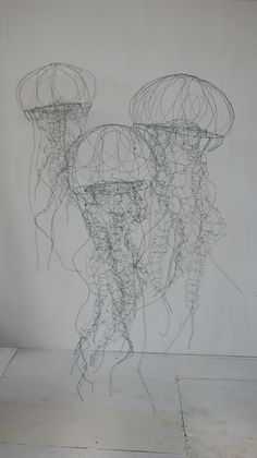 two wire sculptures sitting on top of a white wall