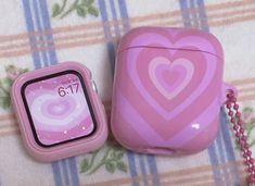 an apple watch and pink heart shaped case sitting on a table next to each other