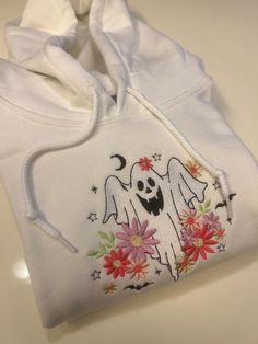 Floral Ghost Embroidered Sweatshirt! It couldn't be fall season without the perfect fall sweater! Embroidered on Gildan 50/50 Cotton/Polyester Blend. Using fall colors, our machine embroiders the cutest fall crewnecks! The perfect outfit for fall outings, watching movies, or going to the pumpkin patch! Embroidered Hoodie For Fall Streetwear, Cute Embroidered Hoodie For Streetwear, Casual Hoodie With Machine Embroidery For Streetwear, Casual Embroidered Hoodie For Streetwear, White Hooded Hoodie With Embroidered Graphics, White Hoodie With Custom Embroidery For Winter, White Embroidered Hoodie For Streetwear, Casual Halloween Top With Embroidered Logo, Cute Winter Hoodie With Embroidered Graphics