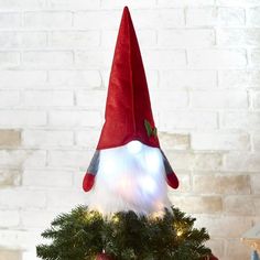 an elf's hat is sitting on top of a christmas tree with white lights