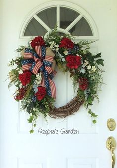 a patriotic wreath with flowers and greenery hangs on the front door of a home