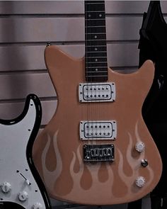 an electric guitar with flames painted on it's body next to a black and white guitar