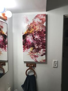 two paintings hang on the wall above a sink in a bathroom with towels hanging from hooks