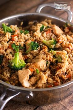 a pan filled with rice and broccoli on top of a wooden table