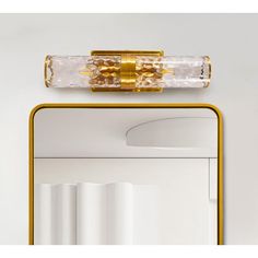 a bathroom mirror with a gold frame and clear glass on it's face, next to a white wall