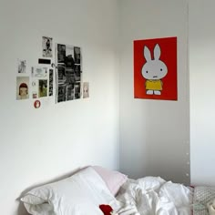 an unmade bed in a bedroom with pictures on the wall and posters above it