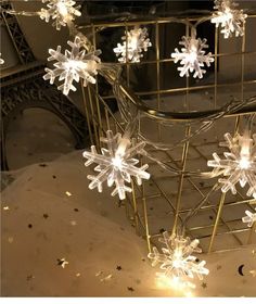 snowflakes are hanging from a wire basket in front of a mirror with stars on it