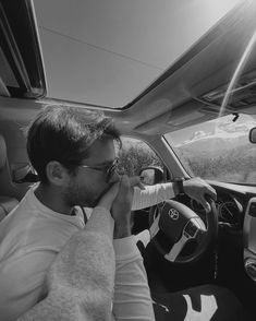 a man sitting in the driver's seat of a car talking on a cell phone