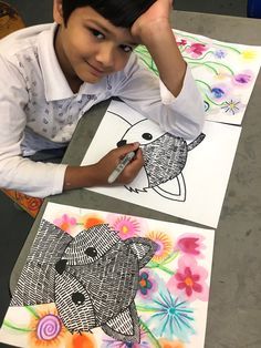 a young boy sitting at a table with some art work on the paper he made