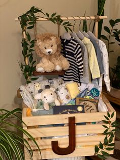 a teddy bear sitting on top of a wooden crate filled with baby clothes and toys