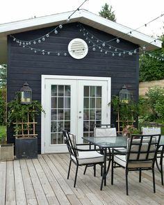 an outdoor dining area with patio furniture and string lights on the side of the house