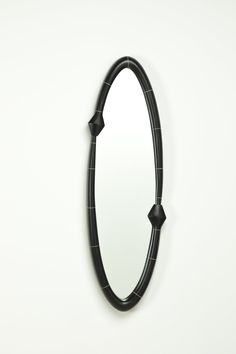 a black oval mirror hanging on the wall