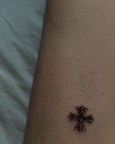 a small cross tattoo on the ankle is shown in black and grey ink with white background