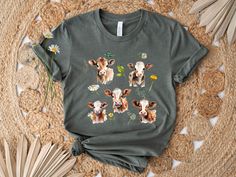 a t - shirt with cows and daisies on the front, sitting on a rug