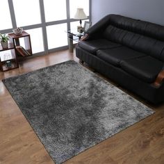 a living room with a black leather couch and wooden flooring on the hardwood floors