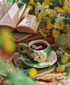 a cup of coffee sitting on top of a saucer next to books and flowers