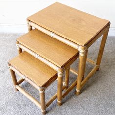 three bamboo nesting tables on carpeted area with white wall in the backgroud