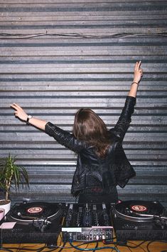 a woman with her arms up in front of two dj's