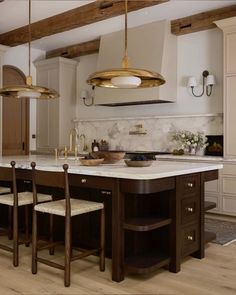 a large kitchen with an island and two pendant lights hanging from it's ceiling