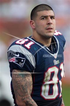 a close up of a football player with tattoos on his arm and shoulder, looking off to the side