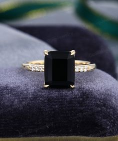 a black diamond ring sitting on top of a velvet cushion