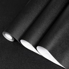 two knives are laying next to each other on a black leather tablecloth with white trim