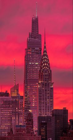 the city skyline is lit up at night with pink and red skies in the background