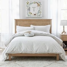 a bed in a bedroom with white curtains and pillows on the headboard, along with a stuffed animal