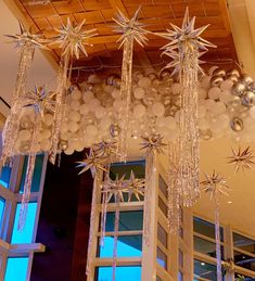 a chandelier hanging from the ceiling in front of windows with balloons and starbursts