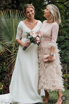 two women standing next to each other wearing dresses and holding bouquets in their hands