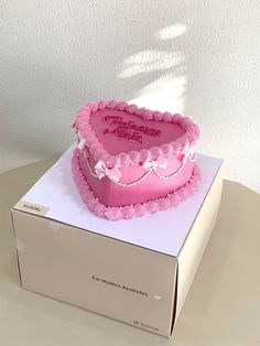 a pink heart shaped cake sitting on top of a box