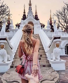 a woman in a pink dress is walking up some steps with her hand on her hip