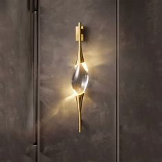 a wall light that is on the side of a metal door with a glass vase in front of it