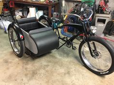 an old style motorcycle with a side car attached to the front wheel is parked in a garage