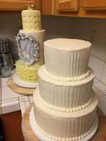 three tiered white cake sitting on top of a wooden table next to a kitchen counter