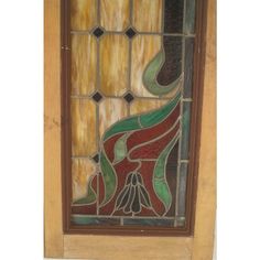 an old stained glass window with flowers and leaves on the bottom half, in brown wood frame