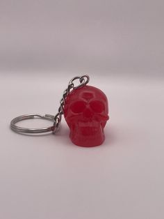 a red plastic skull keychain with a metal chain hanging from it's side