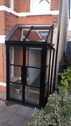 a small black glass house sitting on the side of a building