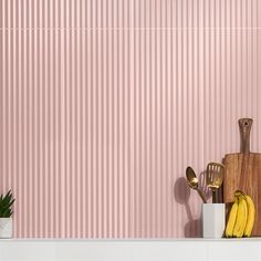 a kitchen with pink wallpaper and wooden utensils on the counter next to a cutting board