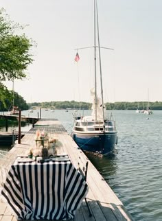 a boat is docked at the end of a pier with a striped table cloth on it